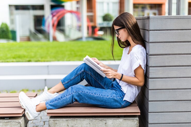 relaxed-woman-reading-hard-cover-book-sunset-sitting-bench_231208-2086